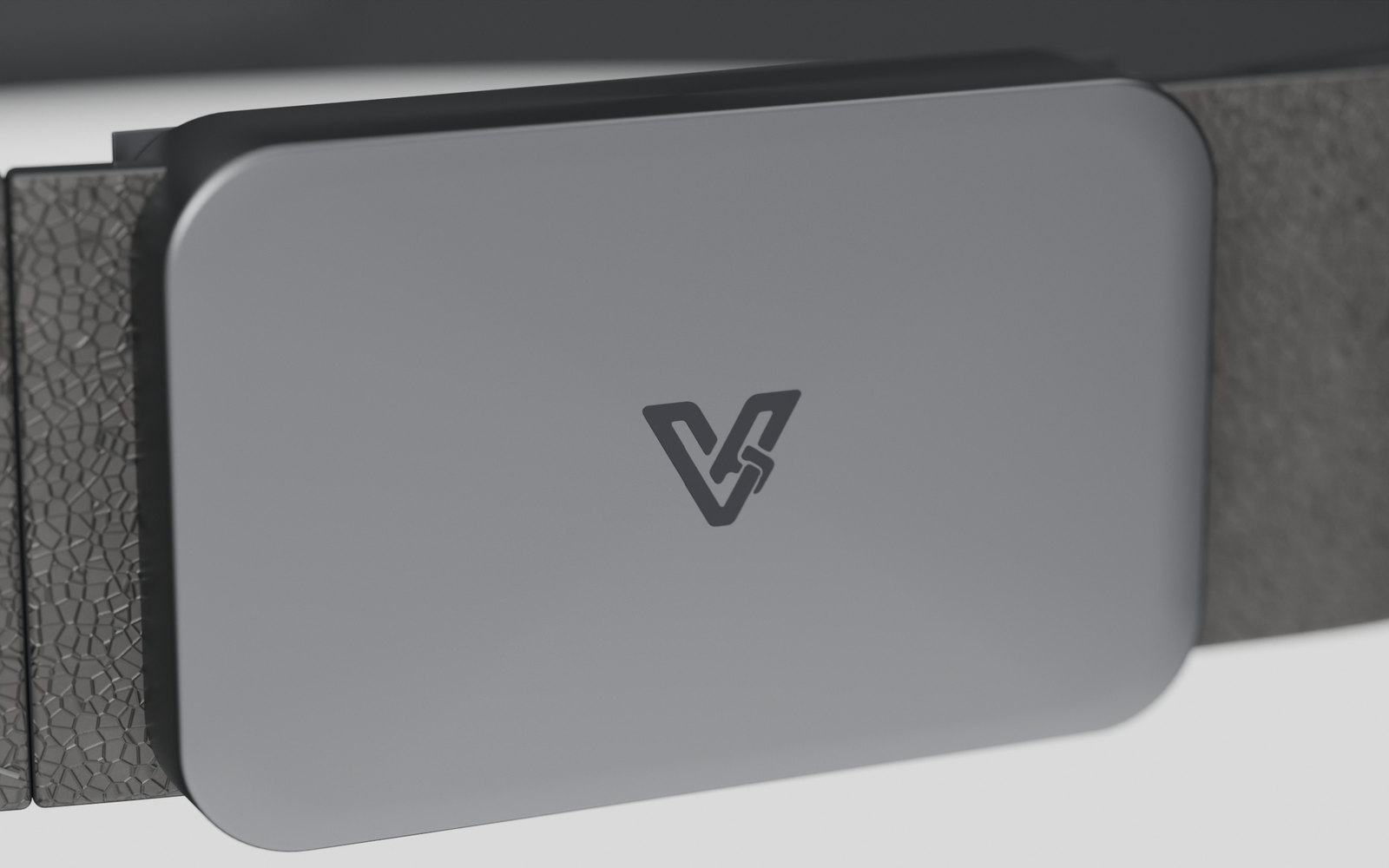 Close view of the Vyldor buckle face: matte anodised graphite with the Vyldor mark etched tone on tone